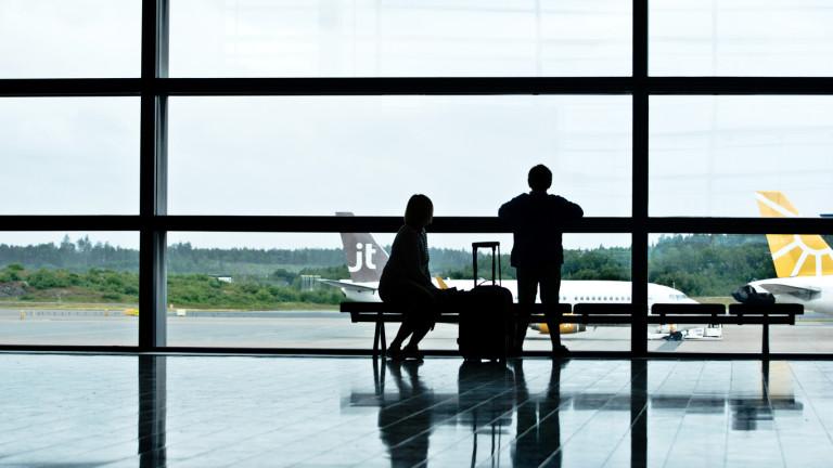 Silhouette of waiting tourists/passengers (a mother and child) at the departure terminal in Stockholm Arlanda Airport Sweden (IATA: ARN, ICAO: ESSA). Jet Time Airplane on the runway at the background