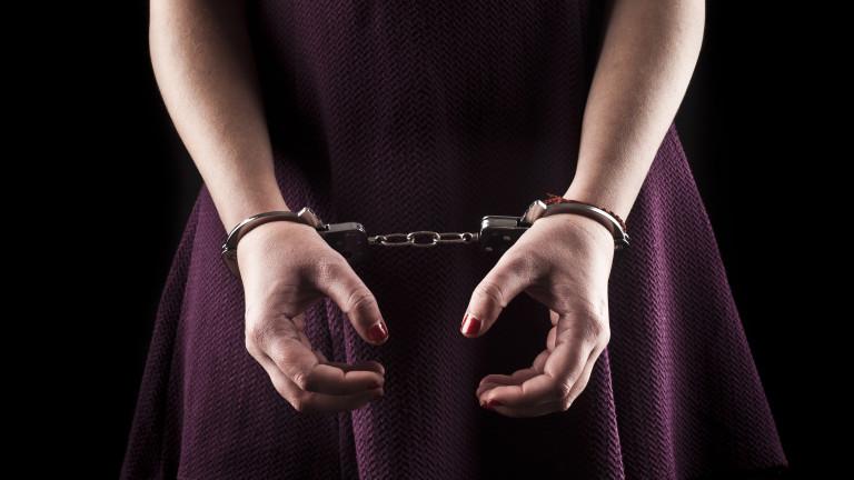 submissive woman wearing a purple dress in metal handcuffs