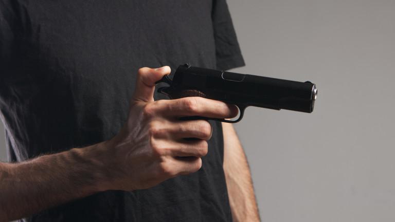 a man holding a black pistol in his hand threatening