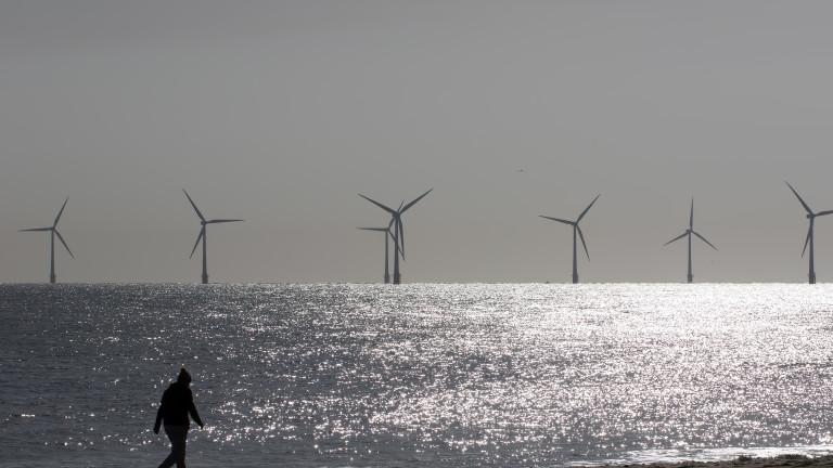 Beach walk. Morning coronavirus lockdown isolation exercise by wind turbines