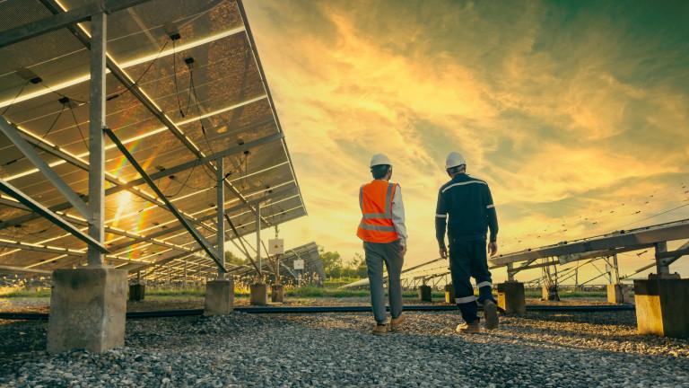 Low angle view of technician walks with investor through field of solar panels, Alternative energy to conserve the world's energy, Photovoltaic module idea for clean energy production
