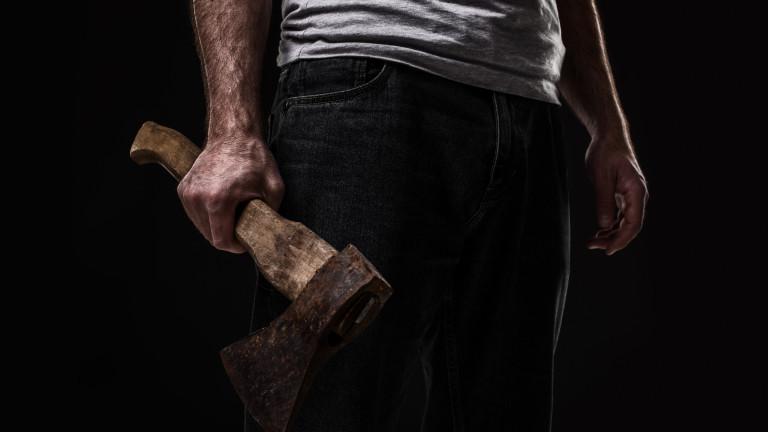 A man holds an ax in his hands against on black background