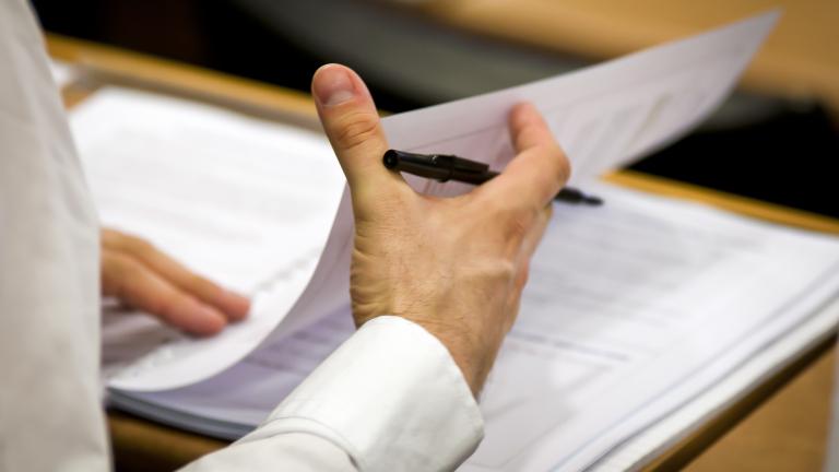 Businessman flipping business papers on a wooden desk