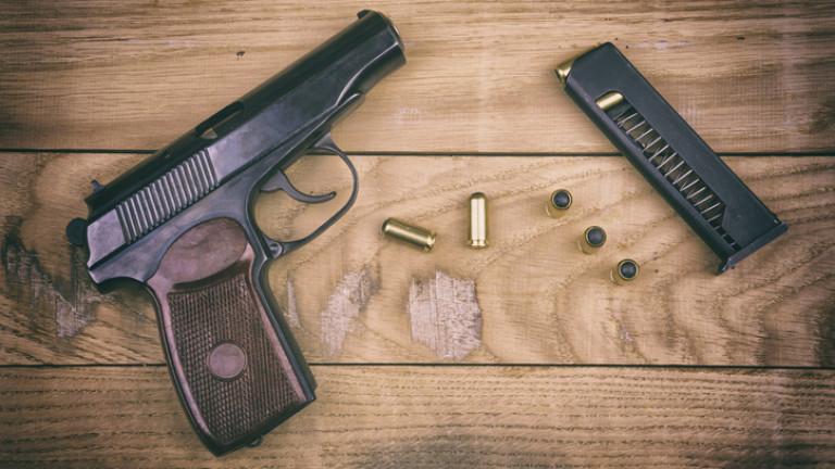 Pistol with bullets and cartridge on the wooden surface, set