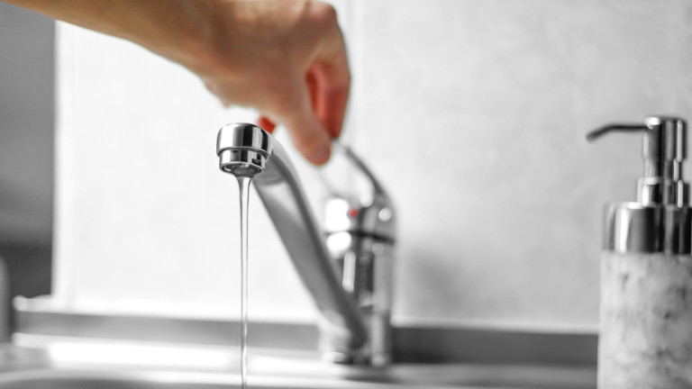 Hand opens the water tap. Close up