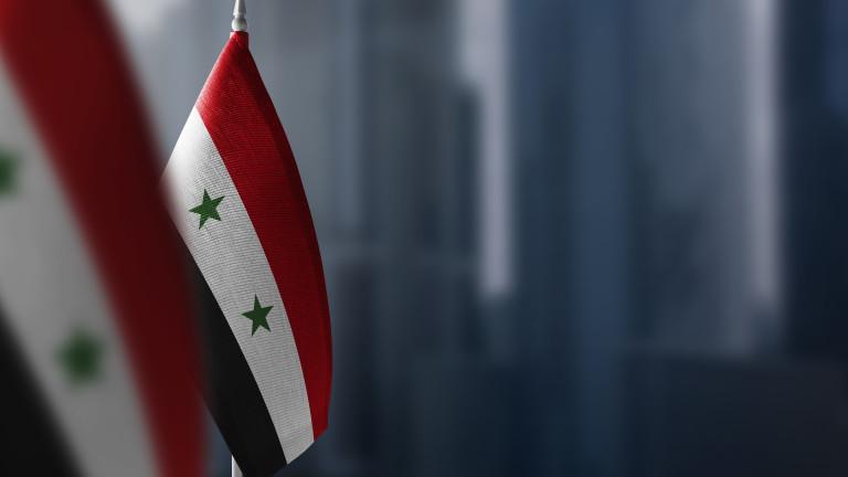 Small flags of Syria on a blurry background of the city