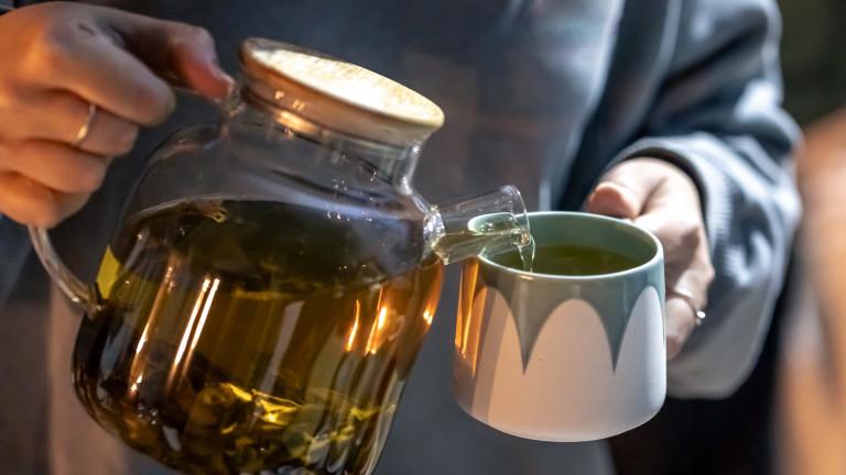 A woman pours tea into a cup late at night.